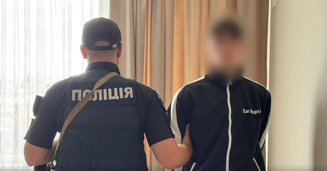 Поліцейський тримає затриманого з розмитим обличчям біля штор
